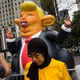 Pedestrians stop and take photos of a 15-foot tall inflatable rat in the likeness of U.S. President Donald Trump at the corner of Fifth Avenue and 59th Street up the road from Trump Tower, August 14, 2017 in New York City.